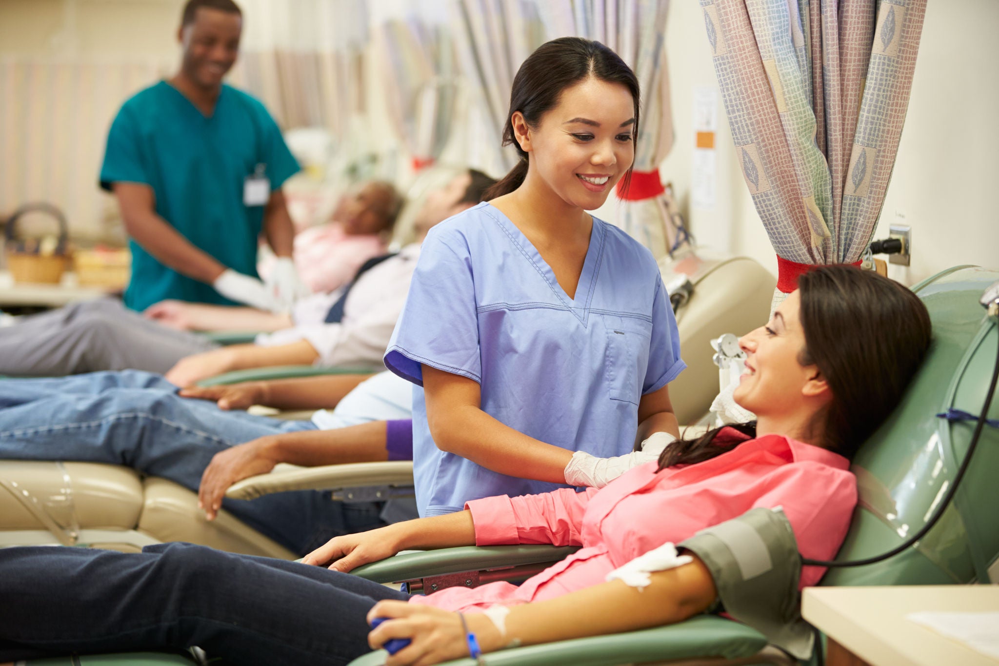 Happy Smiling Blood Donors Making Donation In Hospital