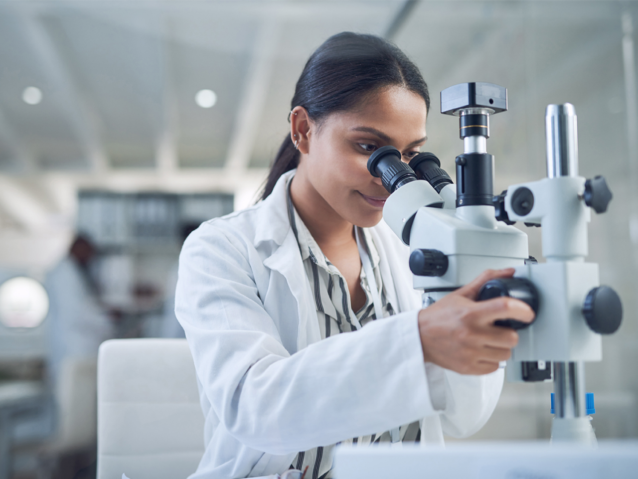 woman looking through microscope