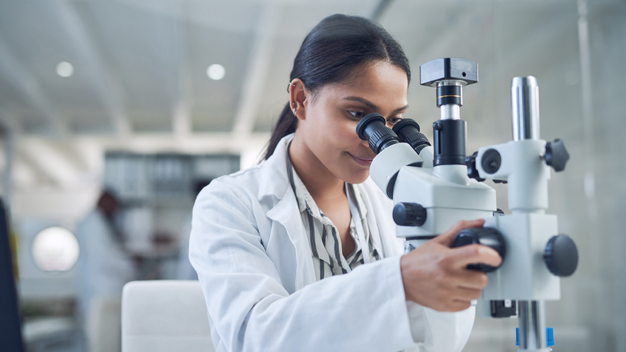 woman looking through microscope